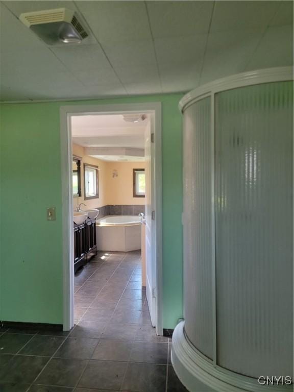 corridor featuring baseboards, a sink, visible vents, and dark tile patterned flooring