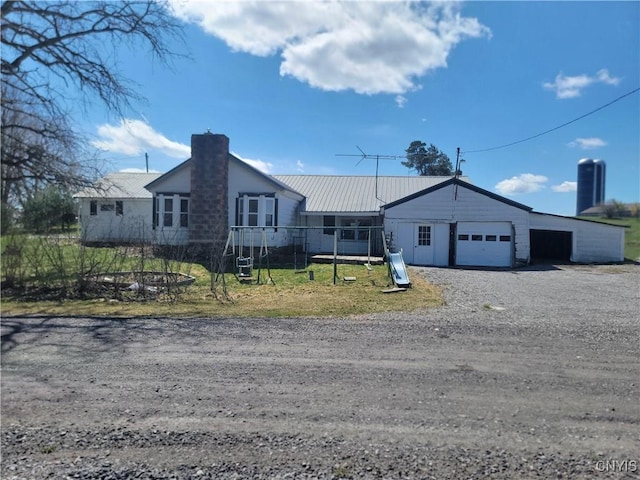 ranch-style house with a garage, a chimney, and metal roof