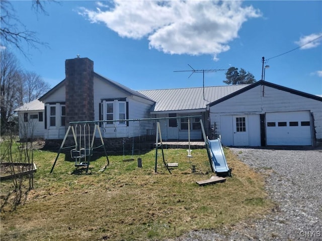 ranch-style home featuring a chimney, a front lawn, a trampoline, and a garage