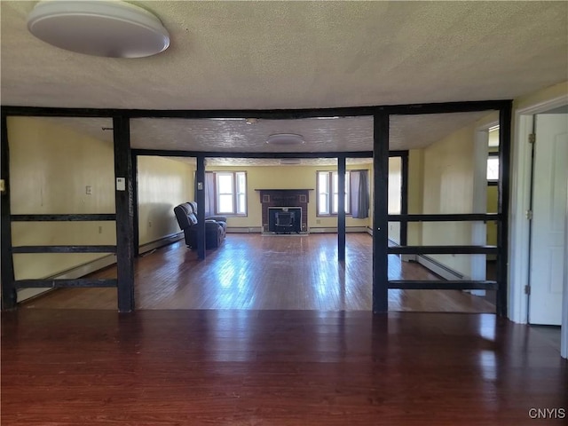 interior space featuring a baseboard radiator, baseboards, wood finished floors, and a textured ceiling
