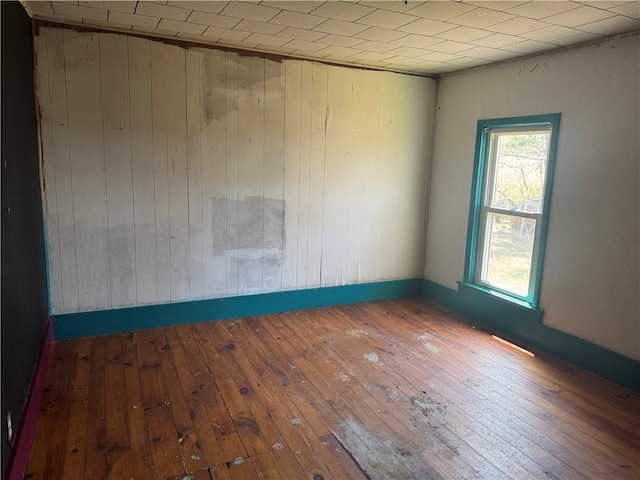 unfurnished room with wood-type flooring and wooden walls