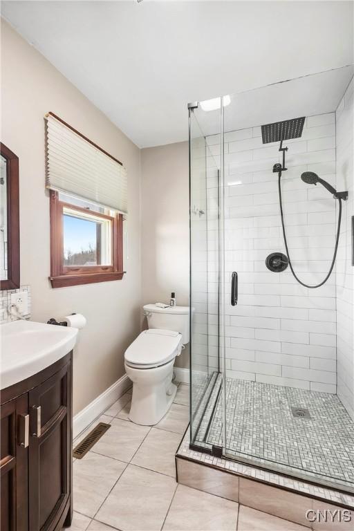 full bathroom with toilet, visible vents, baseboards, a shower stall, and vanity