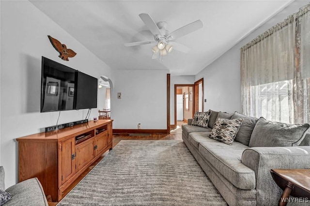 living room with baseboards, wood finished floors, arched walkways, and ceiling fan