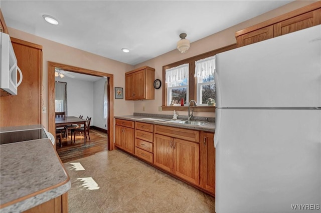 kitchen featuring a sink, baseboards, recessed lighting, white appliances, and brown cabinets