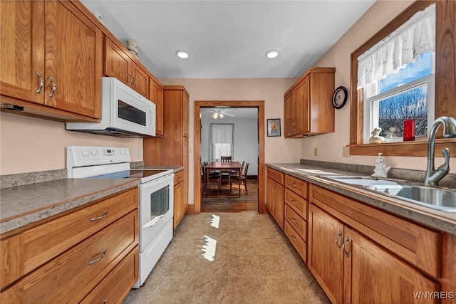 kitchen with a sink, brown cabinetry, white appliances, ceiling fan, and recessed lighting