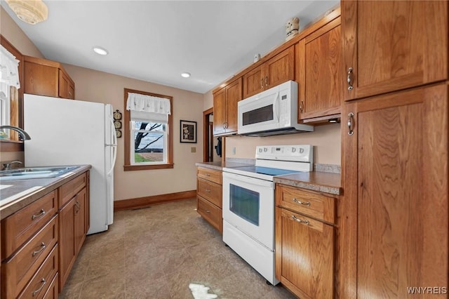 kitchen featuring a sink, brown cabinetry, white appliances, baseboards, and recessed lighting