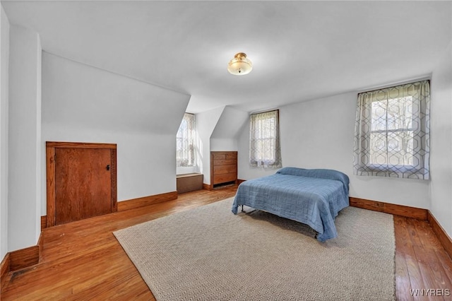 bedroom featuring baseboards, vaulted ceiling, and wood finished floors