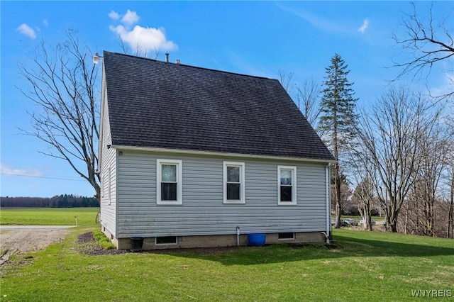 view of side of home with roof with shingles and a yard