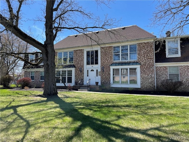 view of front of property featuring brick siding, a shingled roof, and a front yard