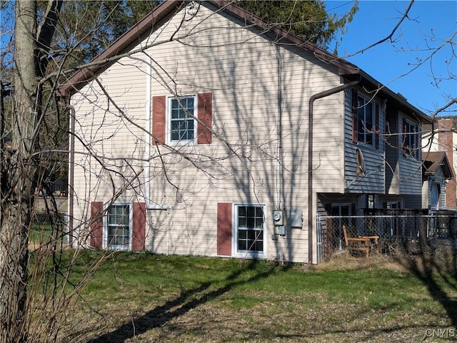 view of side of home with fence and a yard