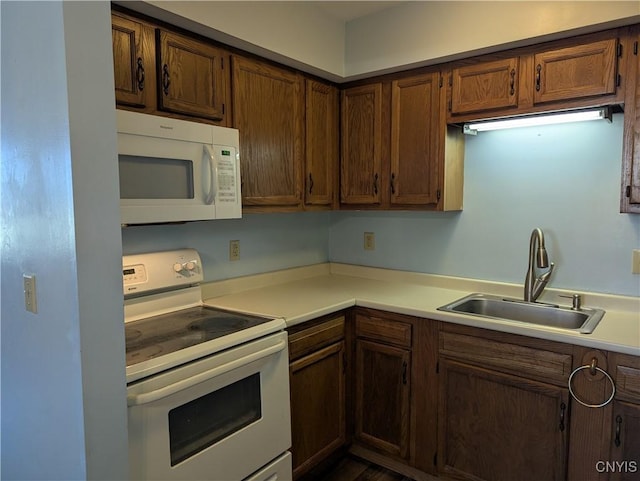 kitchen with light countertops, a sink, and white appliances