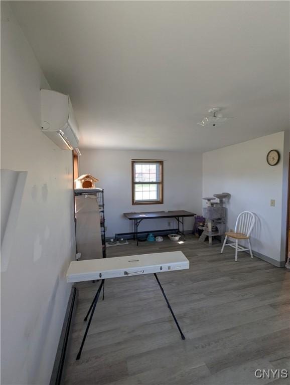 interior space featuring baseboards, wood finished floors, and a wall mounted air conditioner