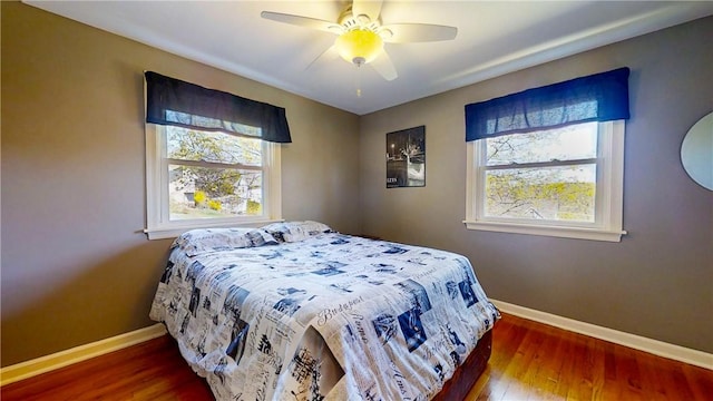 bedroom with baseboards, wood finished floors, and multiple windows