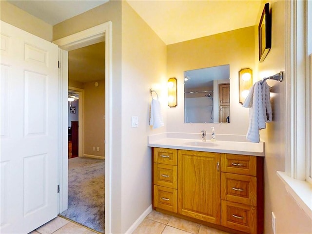 bathroom featuring baseboards, tile patterned flooring, vanity, and a shower