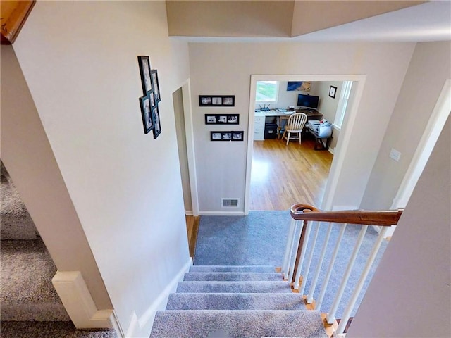 staircase with visible vents, carpet flooring, and baseboards