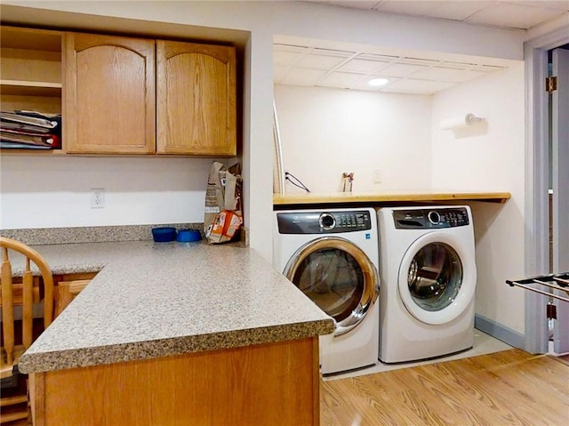 clothes washing area with light wood-style floors, laundry area, and separate washer and dryer