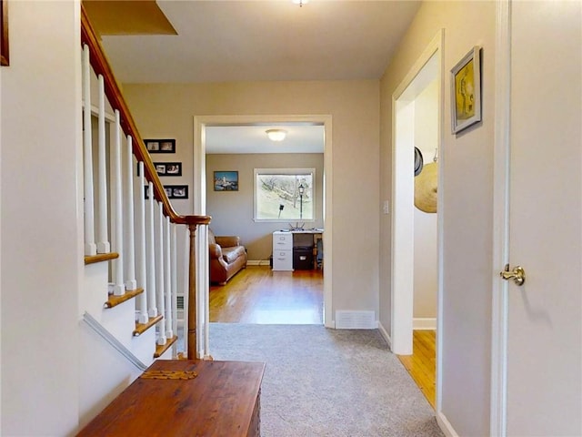 corridor featuring baseboards, carpet flooring, and stairs