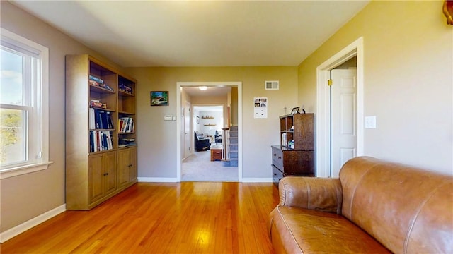 living area featuring baseboards, a healthy amount of sunlight, visible vents, and light wood-style flooring