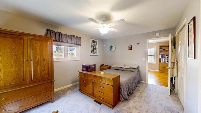 bedroom with a ceiling fan, baseboards, and light carpet