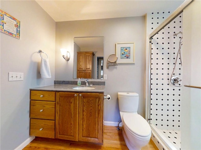 full bathroom with baseboards, toilet, wood finished floors, and a stall shower
