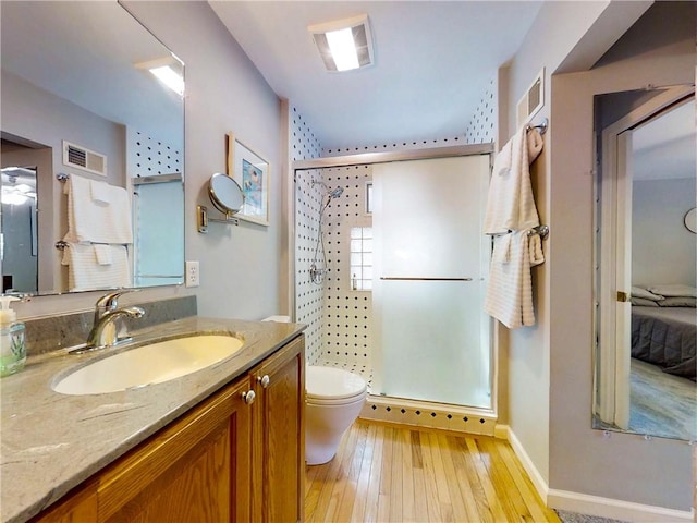 bathroom featuring toilet, visible vents, a shower stall, vanity, and wood-type flooring