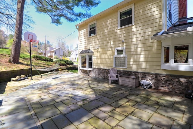 rear view of house featuring stone siding and a patio area