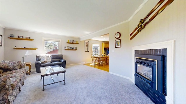 living room with carpet floors, ornamental molding, a glass covered fireplace, and baseboards