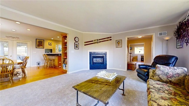 living room with a healthy amount of sunlight, crown molding, visible vents, and carpet