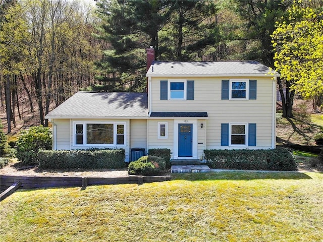 traditional-style house with a front lawn, a chimney, and central AC