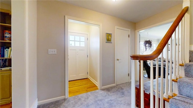carpeted entrance foyer with stairs and baseboards