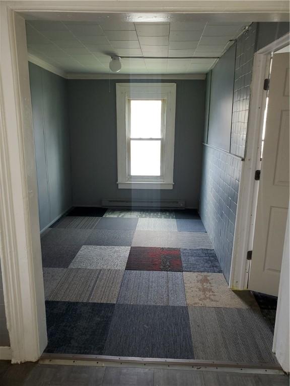 empty room featuring a baseboard heating unit and a paneled ceiling