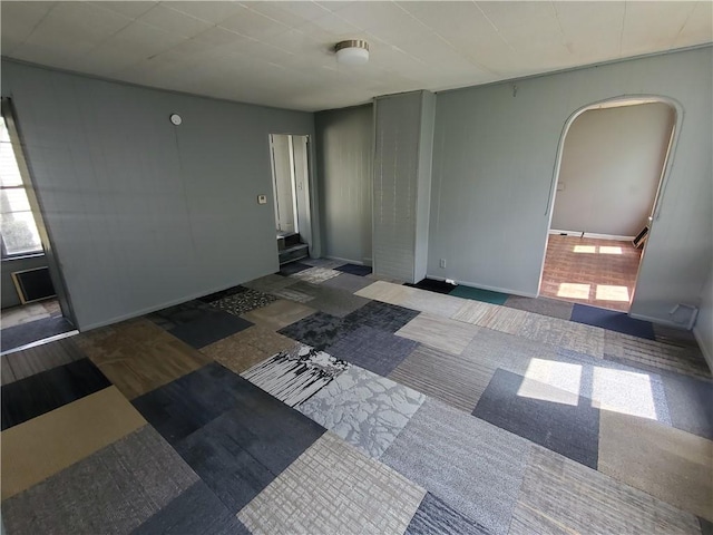 empty room featuring arched walkways and baseboards