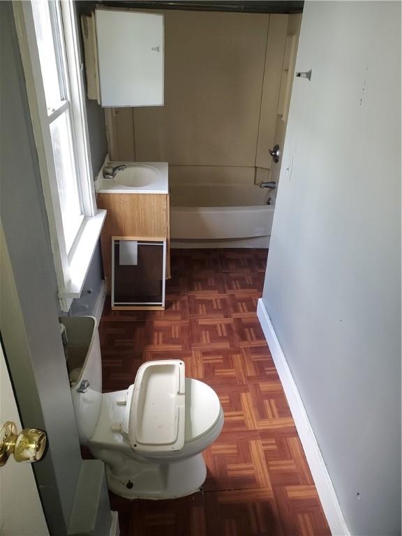 full bathroom with a bath, baseboards, a sink, and toilet