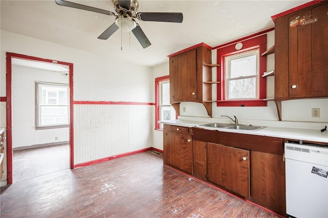 kitchen featuring open shelves, wood finished floors, white dishwasher, a sink, and light countertops
