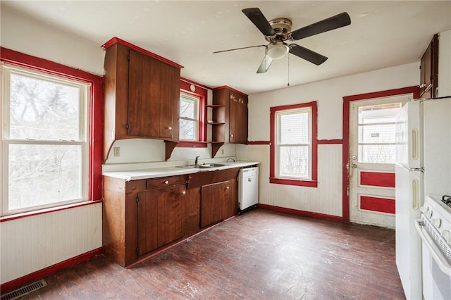 kitchen with a sink, white appliances, visible vents, baseboards, and dark wood-style floors