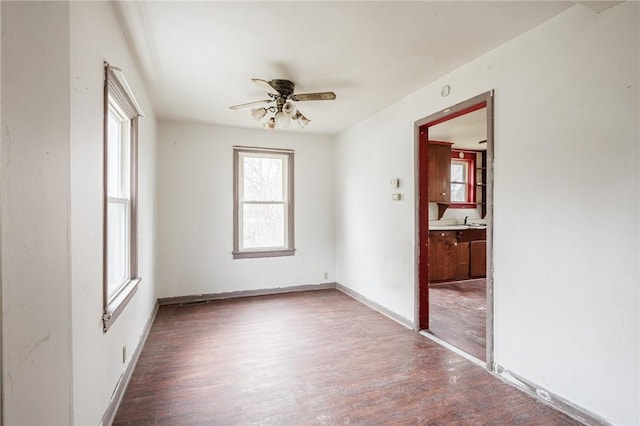 spare room featuring wood finished floors, a healthy amount of sunlight, and a ceiling fan