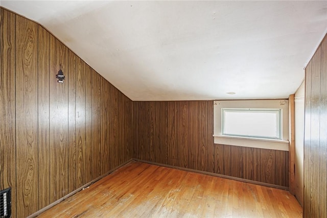 additional living space featuring wood walls, lofted ceiling, and hardwood / wood-style floors