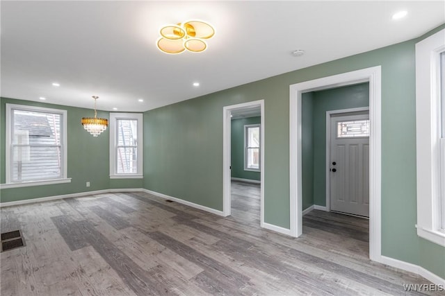 interior space with baseboards, visible vents, an inviting chandelier, recessed lighting, and wood finished floors