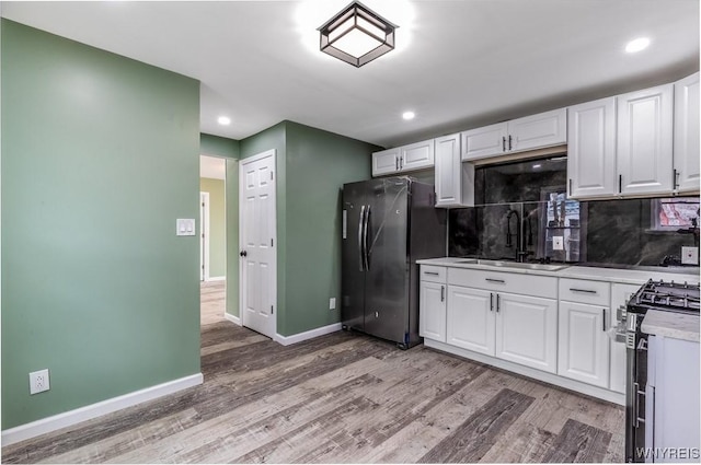 kitchen with white cabinets, appliances with stainless steel finishes, a sink, and light wood-style flooring