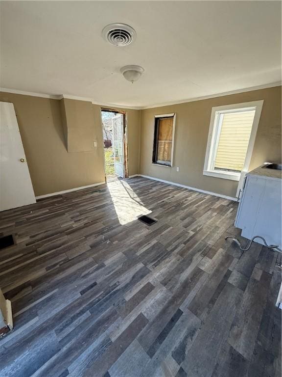 unfurnished living room featuring ornamental molding, baseboards, visible vents, and dark wood-style floors