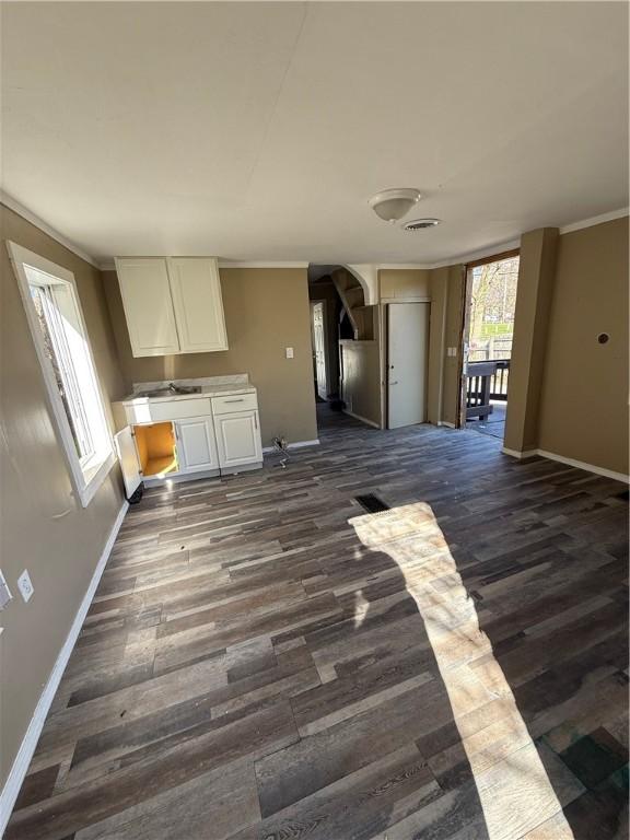 kitchen with dark wood-type flooring, light countertops, white cabinets, and baseboards