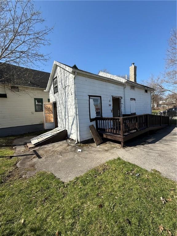 rear view of house featuring a chimney and a deck