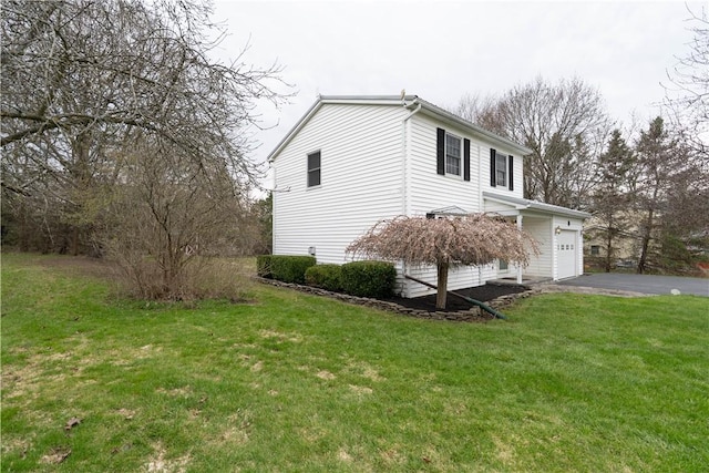 view of side of home featuring aphalt driveway and a yard