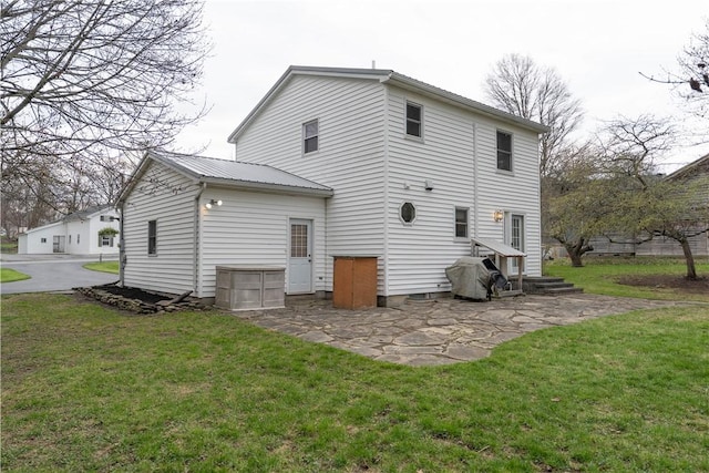 back of property with a lawn, a patio area, and metal roof