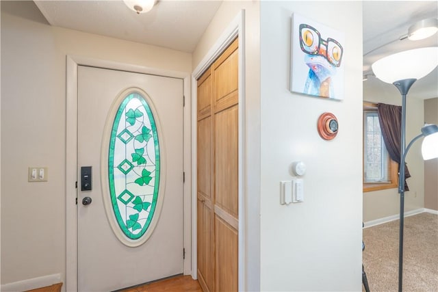 entrance foyer featuring plenty of natural light, baseboards, and light colored carpet
