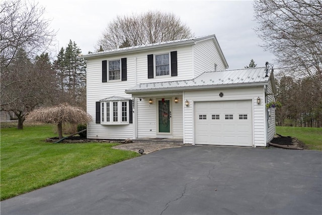 traditional-style home with a garage, a front lawn, metal roof, and aphalt driveway