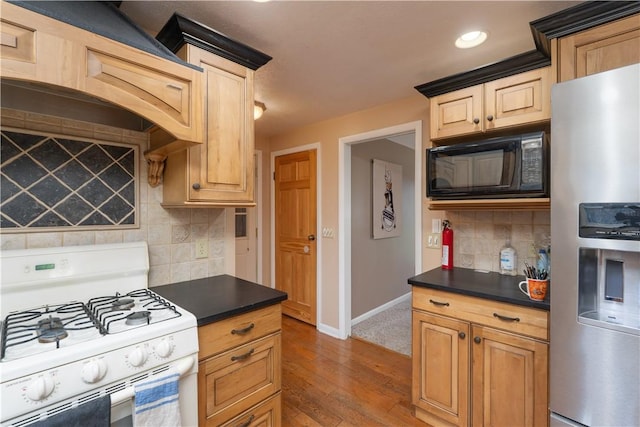 kitchen featuring dark countertops, black microwave, stainless steel refrigerator with ice dispenser, and white range with gas cooktop
