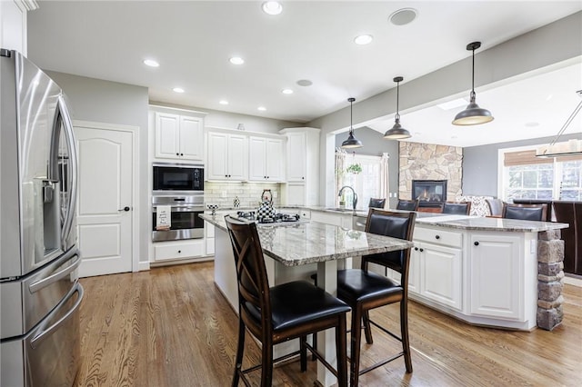 5 Ponds Edge Way, Pittsford, NY 14534 - kitchen with a stone fireplace, a sink, light wood finished floors, appliances with stainless steel finishes, and a kitchen island