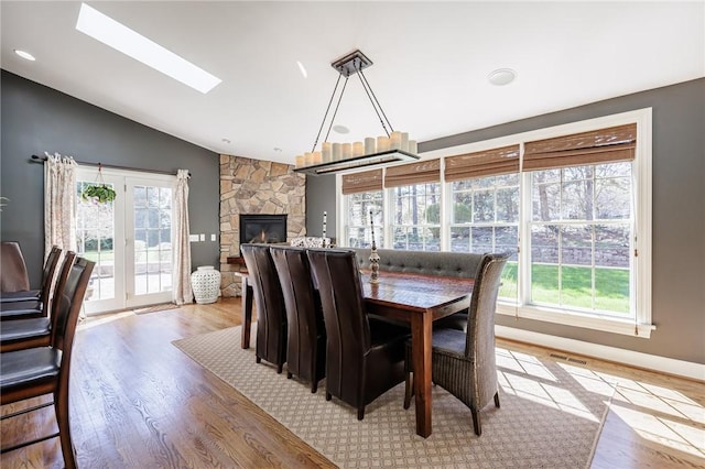 5 Ponds Edge Way, Pittsford, NY 14534 - dining area with plenty of natural light, a stone fireplace, wood finished floors, and vaulted ceiling with skylight