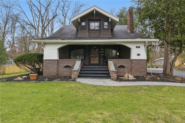 view of front of house with a chimney, brick siding, and a front yard